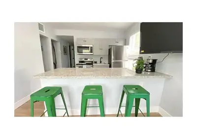 a kitchen with two green stools at a counter at Cozy Duplex near Wynwood & Beach in Miami