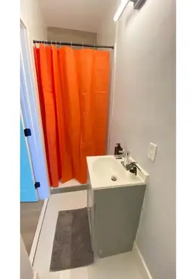 a bathroom with a sink and an orange shower curtain at Cozy Duplex near Wynwood & Beach in Miami