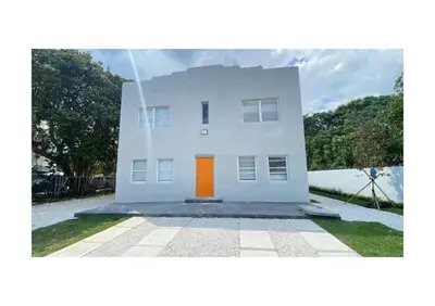 a white house with an orange door in the yard at Cozy Duplex near Wynwood & Beach in Miami