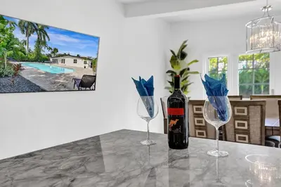 a bottle of wine sitting on a table with two glasses at New ! Pool House 3-bedroom Home Victoria Park in Fort Lauderdale