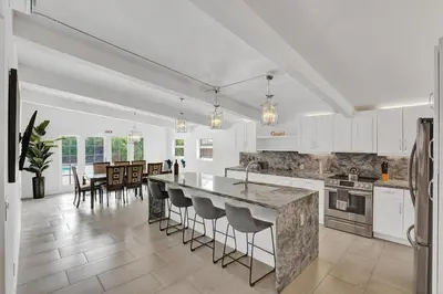 a kitchen with white cabinets and a island with bar stools at New ! Pool House 3-bedroom Home Victoria Park in Fort Lauderdale