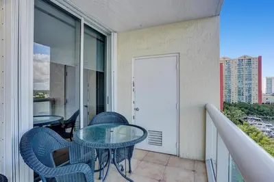 a patio with a glass table and chairs on a balcony at Le Petit Italie ,water View 22 With Pool in Sunny Isles Beach
