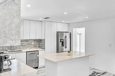 a kitchen with white cabinets and a stainless steel refrigerator at waterfront Ocean dream House Hollywood Hard Rock airport in Fort Lauderdale