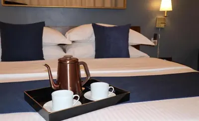 a tray with two cups and a tea kettle on a bed at Hotel Downtown Miami - DQR in Miami