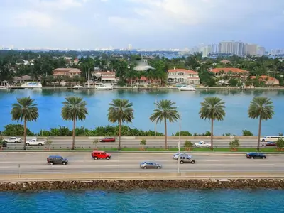 a highway with cars and palm trees next to a river at Wynwood Area with Hot Tub, 10 min from South Beach in Miami