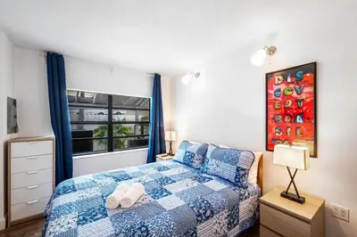 a bedroom with a blue and white bed and a window at West Brickell GEM With Private Garden, 2BR 2BATH in Miami