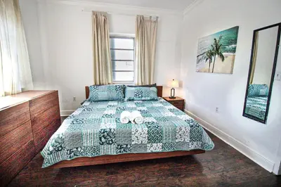 a bedroom with a bed with a green and white comforter at 3 Bedroom Apartment with BBQ and Patio, Near Brickell in Miami