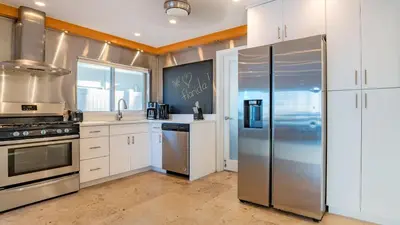 a kitchen with white cabinets and a stainless steel refrigerator at Winter Rate Discount Beachside Home Pool Views Beach Haven by AvantStay in Fort Lauderdale