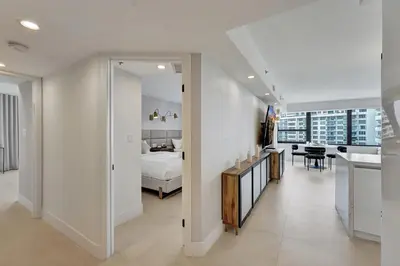 a white bedroom with a bed and a kitchen at Beautiful Oceanfront 3BDR Condo 801 in Miami Beach