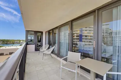 a balcony with white chairs and a table and some windows at Beautiful Oceanfront 3BDR Condo 801 in Miami Beach