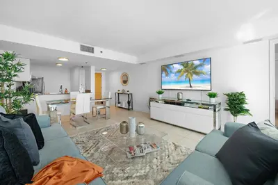 a living room with a blue couch and a table at Stylish 2BR With Skyline Views, Free Parking, Sleeps 8 in Miami