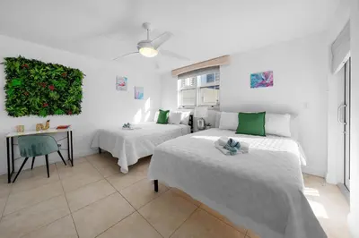 a bedroom with two beds and a table and a green wall at Stylish 2BR With Skyline Views, Free Parking, Sleeps 8 in Miami