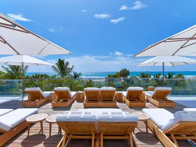 a patio with lounge chairs and umbrellas and the ocean at 1 Hotel South Beach in Miami Beach