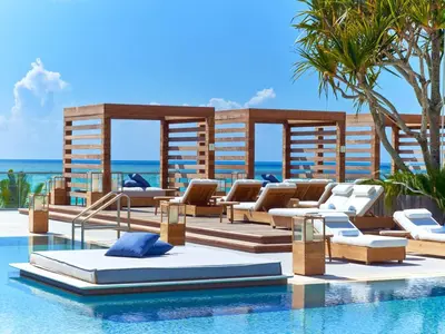 a resort swimming pool with lounge chairs and the ocean at 1 Hotel South Beach in Miami Beach