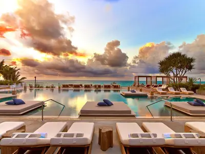 a swimming pool with lounge chairs and the ocean at 1 Hotel South Beach in Miami Beach