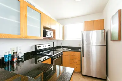 a kitchen with a stainless steel refrigerator and wooden cabinets at Spacious Apt in the heart of South Beach in Miami Beach