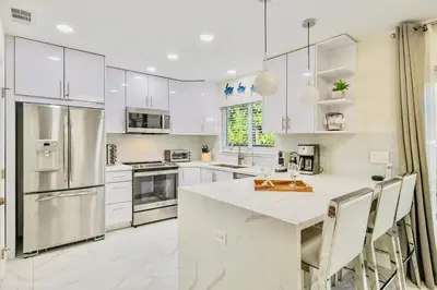 a kitchen with white cabinets and a white counter top at Coastal Paradise Retreat- Mini Golf, 4 Bedrooms, Game Room, Htd Pool, BBQ Fire Pit in Hollywood