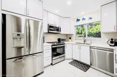 a kitchen with white cabinets and stainless steel appliances at Coastal Paradise Retreat- Mini Golf, 4 Bedrooms, Game Room, Htd Pool, BBQ Fire Pit in Hollywood