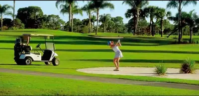 a woman hitting a golf ball with a golf cart at Coastal Paradise Retreat- Mini Golf, 4 Bedrooms, Game Room, Htd Pool, BBQ Fire Pit in Hollywood