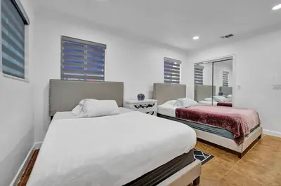 a bedroom with two beds and two windows at Beautiful Tropical Vacation House close to Beach in Hollywood