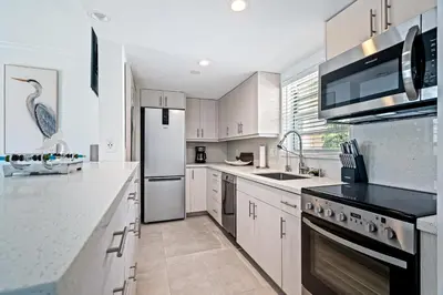 a kitchen with white appliances and a bird on the wall at Walk to Ft Lauderdale beach - Water Views & Pool in Fort Lauderdale