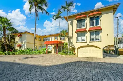 a large yellow building with palm trees in the background at Walk to Ft Lauderdale beach - Water Views & Pool in Fort Lauderdale