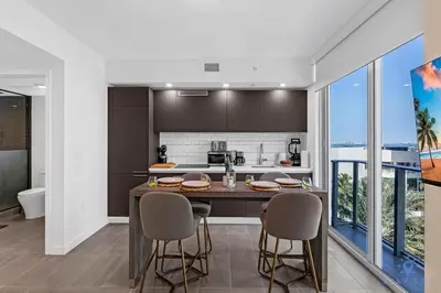 a kitchen with a island with chairs and a counter top at Beautiful Studio Amazing Pool Gym Bar and Spa in Miami