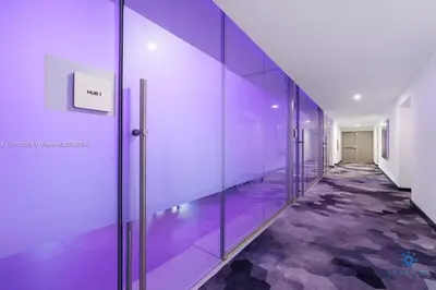 an empty hallway with purple walls and glass doors at Beautiful Studio Amazing Pool Gym Bar and Spa in Miami