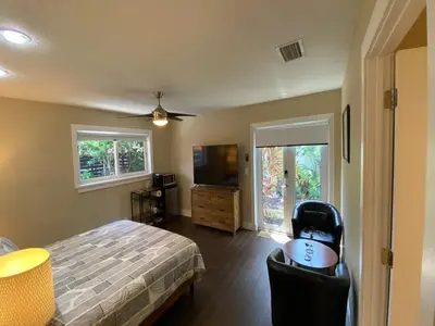 a bedroom with a bed and a television and a chair at Riverbank Guesthouse Wilton Manors in Fort Lauderdale