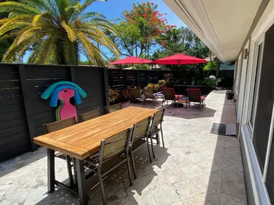 a wooden table and chairs with a painting on a fence at Riverbank Guesthouse Wilton Manors in Fort Lauderdale