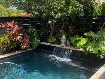 a small pool with a waterfall in a garden at Riverbank Guesthouse Wilton Manors in Fort Lauderdale