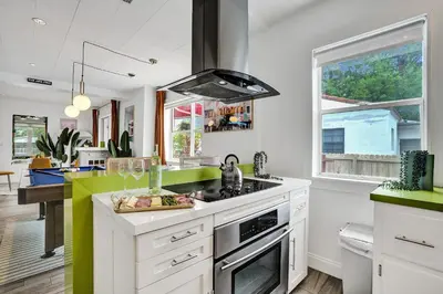a kitchen with white cabinets and green accents at 5 Mins Brickell - Pool & Billiards - Retro Miami in Miami