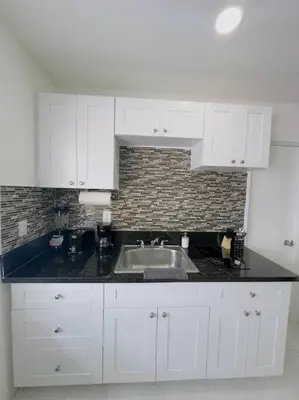 a kitchen with white cabinets and a sink at New Mid Miami Beach apt free parking and beach access in Miami Beach