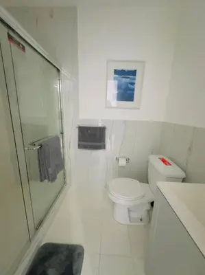 a white bathroom with a shower and a toilet at New Mid Miami Beach apt free parking and beach access in Miami Beach