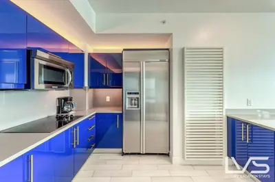 a kitchen with blue cabinets and a stainless steel refrigerator at W FTL 1409 Beachfront Resort 2 Bedroom & 2 Bathroom Condo in Fort Lauderdale