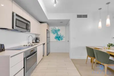 a kitchen with white cabinets and a table in it at Spectacular Apt Infinity View Amazing Amenities in Hallandale Beach