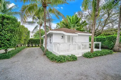 a small white house with palm trees and a driveway at Renovated Grove Bungalow -near Coconut Grove in Miami