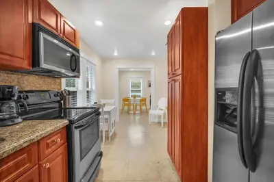 a kitchen with a stainless steel refrigerator and a dining room at Renovated Grove Bungalow -near Coconut Grove in Miami