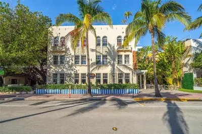 a white building with palm trees in front of a street at Gorgeous coastal PH with Large Private Terrace in Miami Beach