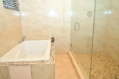 a bathroom with a tub and a glass shower at Luxury home 5 minutes from stadium in Miami