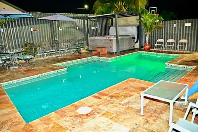 a swimming pool with a table and a chair in it at Luxury home 5 minutes from stadium in Miami
