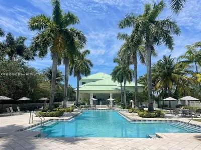 a pool with palm trees in front of a building at Doral Pool 404 by Wave Properties in Miami