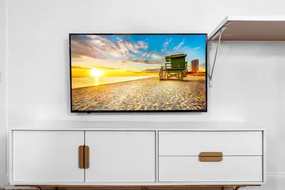 a tv on a white cabinet with a white wall at Luxuri Suites in Miami Beach
