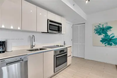 a white kitchen with a sink and a microwave at Beautiful 2BR Balcony Pool Near Beach & Fun in Hallandale Beach