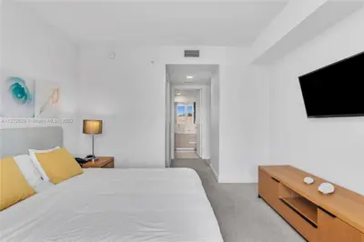 a bedroom with a bed and a flat screen tv at Beautiful 2BR Balcony Pool Near Beach & Fun in Hallandale Beach