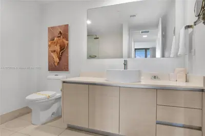 a bathroom with a sink and a toilet and a mirror at Beautiful 2BR Balcony Pool Near Beach & Fun in Hallandale Beach
