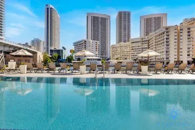 a swimming pool with chairs and umbrellas in a city at Amazing Studio Spectacular Amenities Near Beach in Hallandale Beach