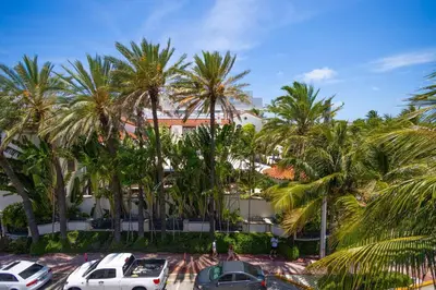 a parking lot with palm trees in front of a building at King Bed-Apt with Rooftop Pool-Bar D303 in Miami Beach