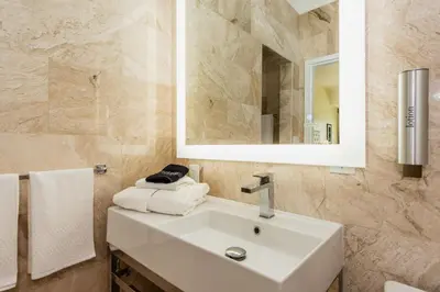 a bathroom with a sink and a mirror and towels at The Link Hotel South Beach in Miami Beach
