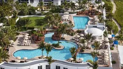 an aerial view of a resort pool with palm trees at Deluxe Studio Balcony Bay View Amazing Pool in Sunny Isles Beach